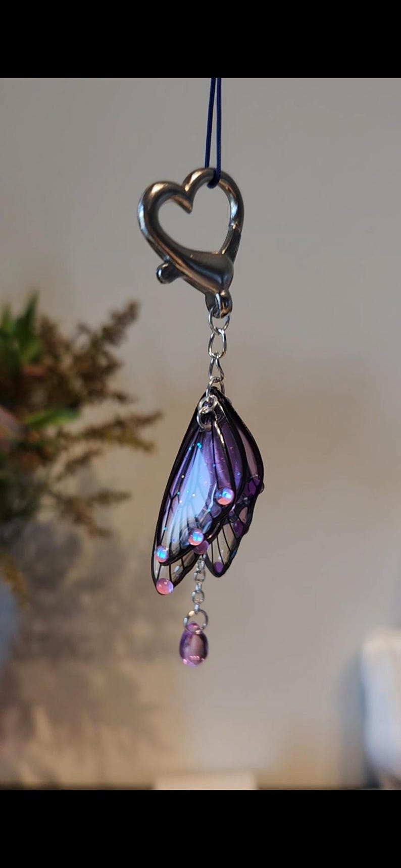 May include: A silver heart-shaped keychain with a purple and white butterfly charm and a dangling purple crystal.
