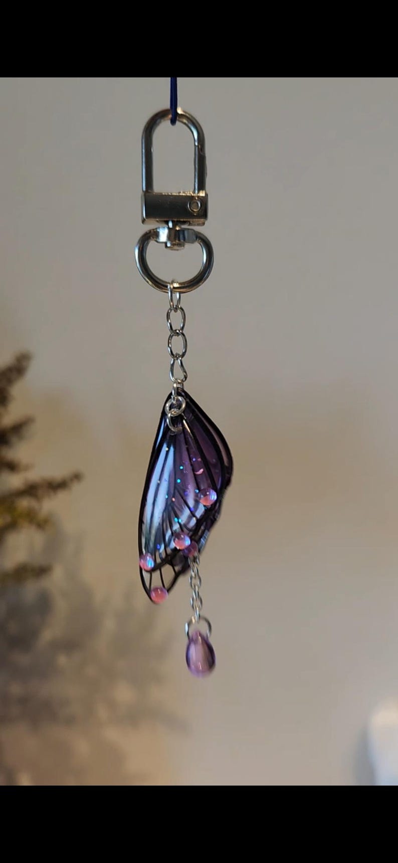May include: A silver key chain with a purple butterfly charm and dangling purple beads.