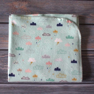 May include: A soft, green baby blanket with a cloud and raindrop pattern. The blanket is made of a soft, plush fabric and is perfect for cuddling.