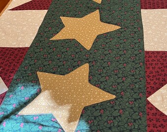 May include: A green, red, and white quilted table runner with a row of three gold stars in the center.