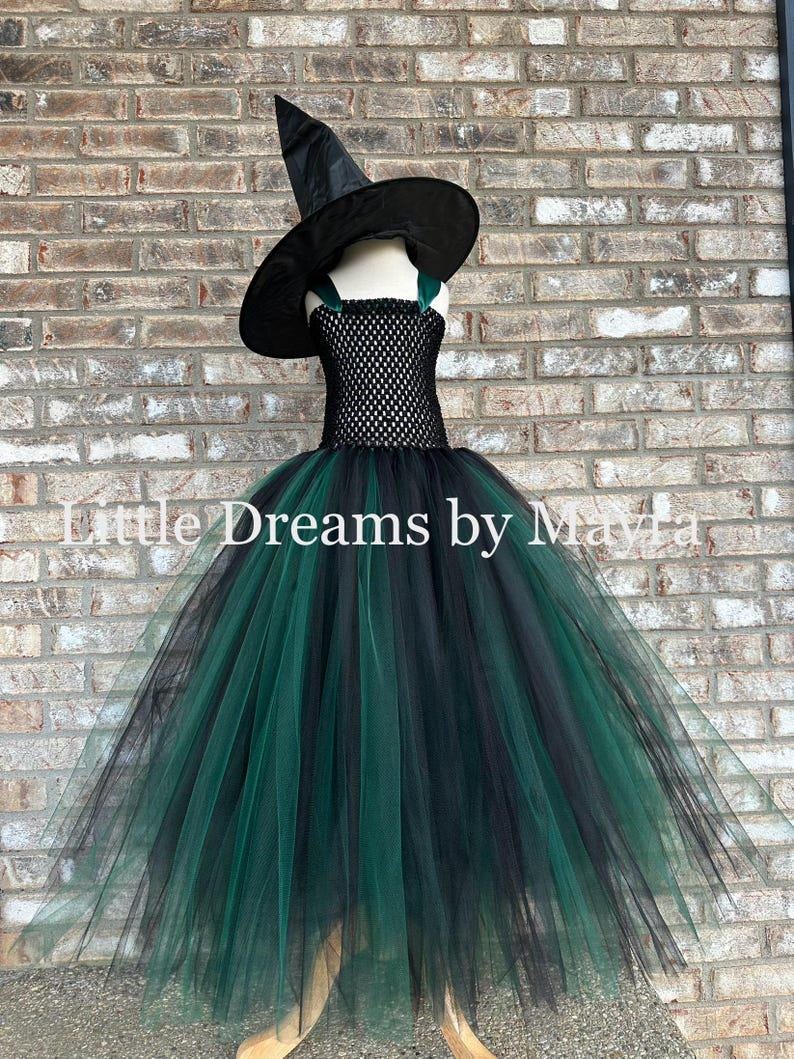 May include: A black and dark green tulle dress featuring a crocheted bodice with dark green shoulder straps, paired with a matching black pointed witch hat. The text Little Dreams by Mayra is overlaid across the center of the image.