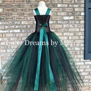 May include: A sleeveless dress featuring a black crocheted bodice and a full, floor-length skirt made of layered black and dark green tulle. A dark green satin ribbon is tied in a bow at the waist. The text Little Dreams by Mayra is visible.