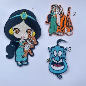 Puede incluir: Tres parches bordados para planchar con personajes de la película de Disney Aladdin. El primer parche es una caricatura de la princesa Jasmine sosteniendo un pequeño tigre. El segundo parche es una caricatura de Jasmine y el tigre Rajah. El tercer parche es una caricatura del Genio.
