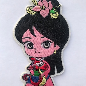 May include: Embroidered iron-on patch featuring a cartoon character with black hair, a pink dress, and a red dragon. The character is wearing a flower in her hair and has a smiling face.