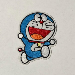 Puede incluir: Parche bordado con el personaje de dibujos animados Doraemon. El parche muestra a Doraemon en una pose de carrera, con un cuerpo azul, detalles blancos y un collar rojo. La boca del personaje está abierta en una amplia sonrisa.