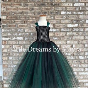 May include: A floor-length dress featuring a black crocheted bodice with dark green shoulder straps and a voluminous skirt made of layered black and dark green tulle. The text Little Dreams by Mayra is overlaid across the center of the image.
