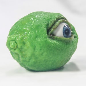May include: A green lime with a large blue eye peeking out from the side.