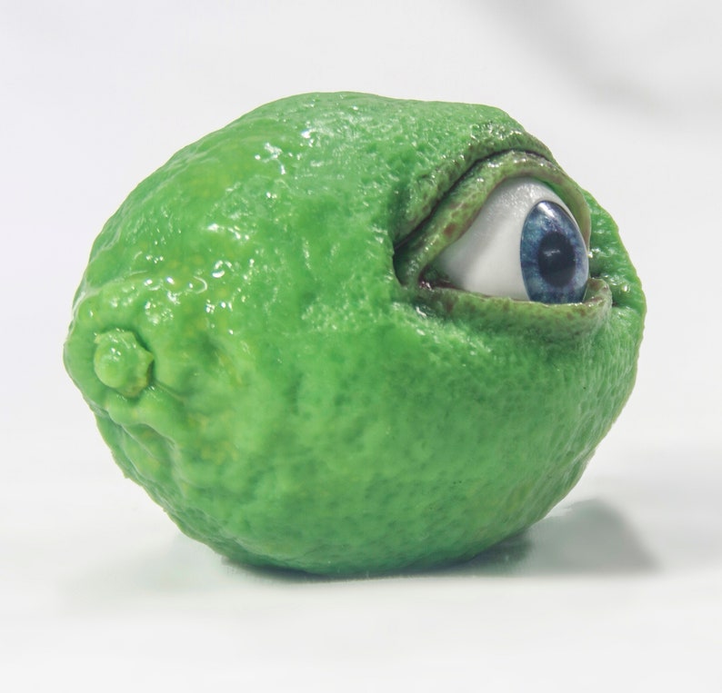May include: A green lime with a large blue eye peeking out from the side.