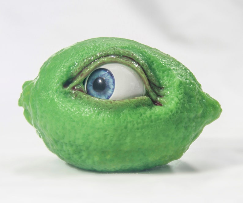 May include: A green lime with a blue eye peering out from the side.