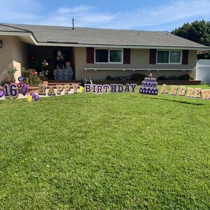 May include: A lawn sign with the text "Happy Birthday Andrew" and a purple cake with a candle. The number 16 is also included in the sign, along with purple and yellow balloons.