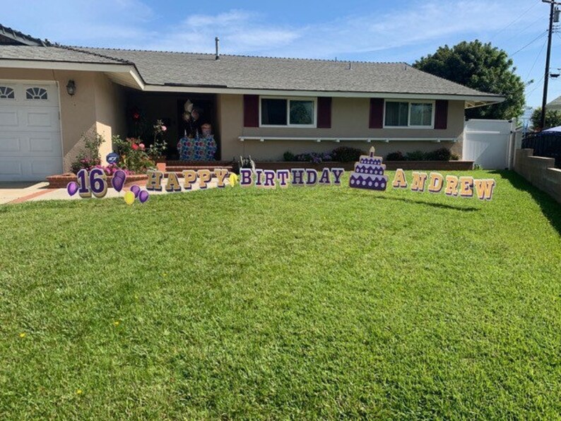 May include: A lawn sign with the text "Happy Birthday Andrew" and a purple cake with a candle. The number 16 is also included in the sign, along with purple and yellow balloons.