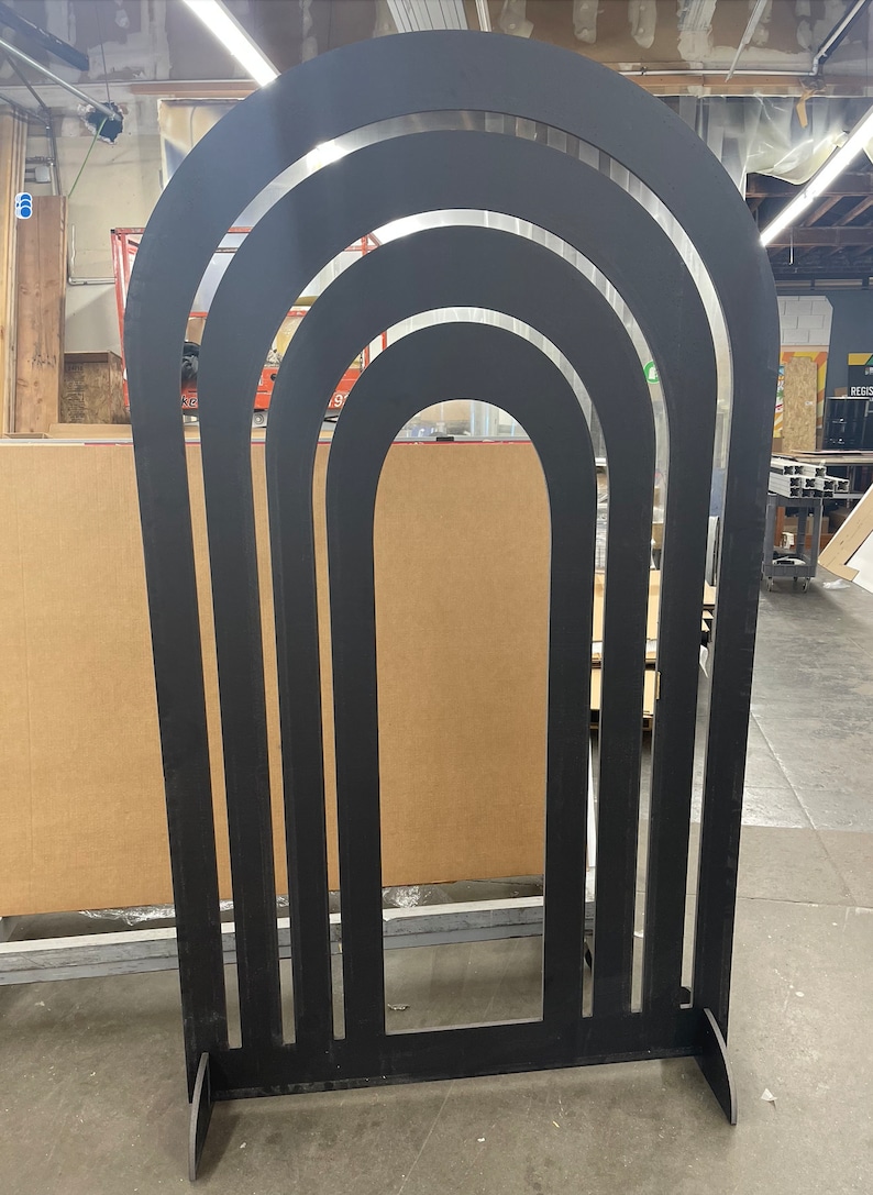 Pu&ograve; includere: Arco nero autoportante in legno con una serie di archi concentrici ritagliati. L'arco &egrave; alto circa 2,1 metri.