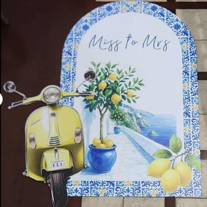 May include: A decorative sign featuring a yellow scooter and a coastal scene with a lemon tree in a blue pot. The sign has the text "Miss to Mrs" and is framed with blue and white patterned borders.