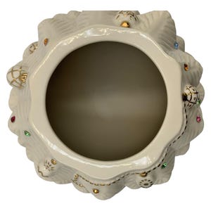 May include: A white ceramic Christmas tree cookie jar with gold trim and colorful jewels. The jar is open and the inside is visible.