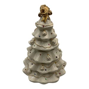 May include: A white ceramic Christmas tree cookie jar with gold trim and colorful ornaments. The tree has a gold bow on top.