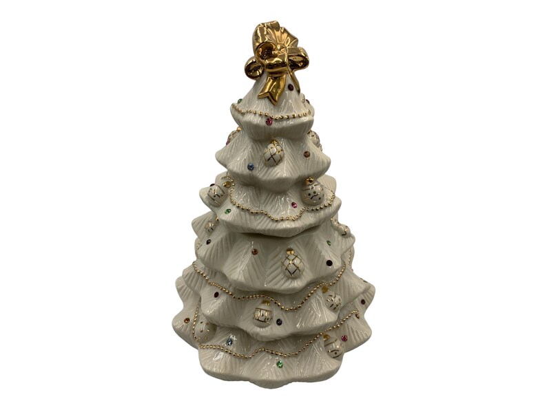 May include: A white ceramic Christmas tree cookie jar with gold trim and colorful ornaments. The tree has a gold bow on top.