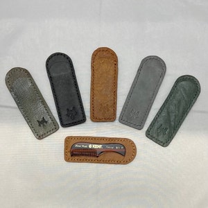May include: Five leather cases in different colors, including black, brown, and gray, with a small brown comb with the text "Hand Made KENT. Super 81T" inside one of the cases.