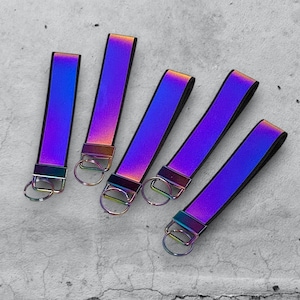 May include: Five iridescent keychains with silver key rings. The keychains are made of a reflective material that shifts colors from purple to blue to green.