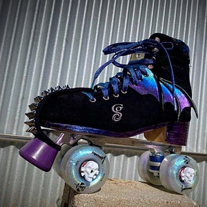 May include: Black roller skates with iridescent purple and blue wings, silver studs, and skull-shaped wheels.