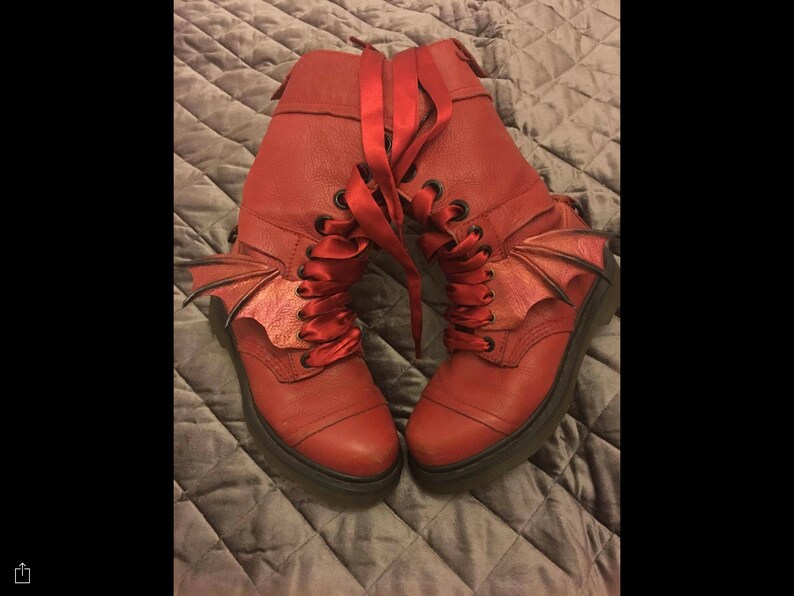 May include: Red leather boots with black laces and red satin ribbon laces. The boots have a bat wing design on the side.