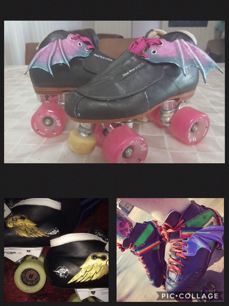 May include: A pair of black roller skates with pink wheels and pink bat wings attached to the sides. The skates have white laces and the words "Hand Made in U.S.A." are printed on the side of the skates.