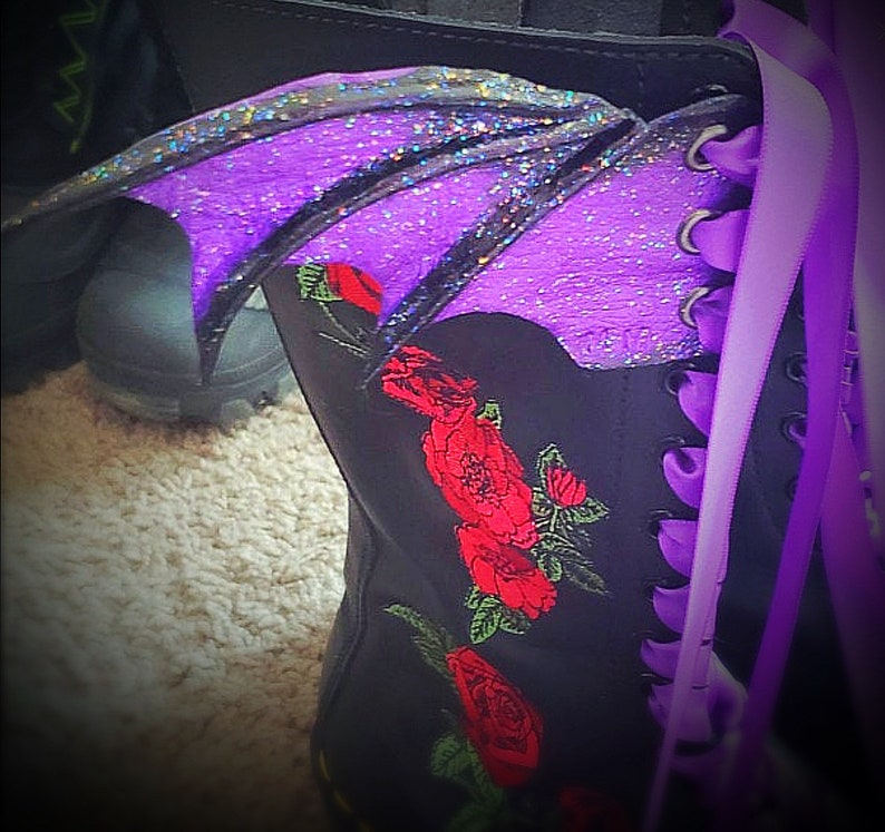 May include: A black boot with purple glitter wings and red embroidered roses. The boot has purple laces.