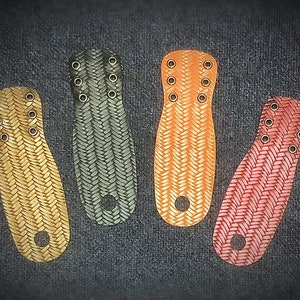 Puede incluir: Cuatro correas de muñeca de cuero en diferentes colores: verde, naranja, amarillo y rojo. Cada correa tiene un patrón tejido y varios agujeros pequeños.