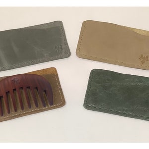 May include: Four leather card holders in different colors, including green and tan. One card holder has a wooden comb inside.