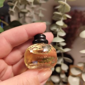 Puede incluir: Un peque&ntilde;o frasco de perfume de vidrio transparente con una tapa negra. El frasco est&aacute; etiquetado con "Yves Saint Laurent 7,5 ml Paris 80% vol."