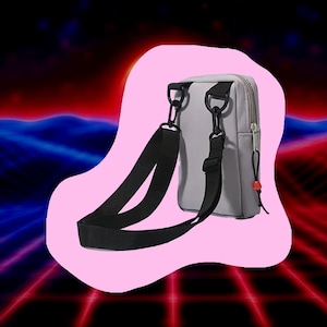 May include: A light gray crossbody bag with a black adjustable strap and black hardware. The bag has a zipper closure and a small red accent. The background is a retro-style design with pink, red, and blue colors.