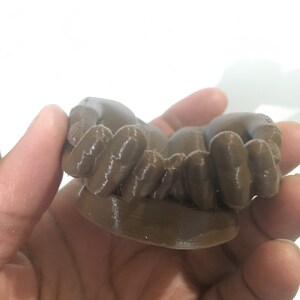 K&ouml;nnte beinhalten: Ein braunes 3D-gedrucktes Objekt mit einer strukturierten Oberfl&auml;che. Das Objekt hat eine abgerundete Form mit mehreren kleinen, abgerundeten Vorspr&uuml;ngen.