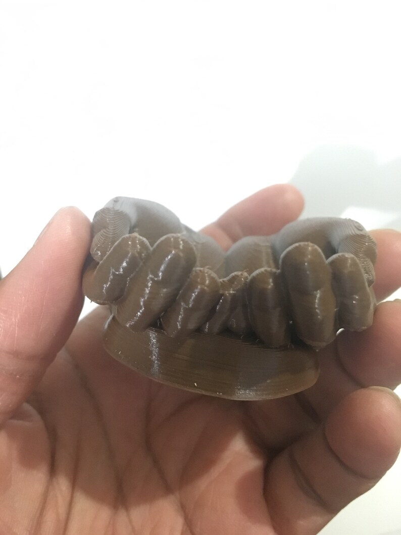 K&ouml;nnte beinhalten: Ein braunes 3D-gedrucktes Objekt mit einer strukturierten Oberfl&auml;che. Das Objekt hat eine abgerundete Form mit mehreren kleinen, abgerundeten Vorspr&uuml;ngen.