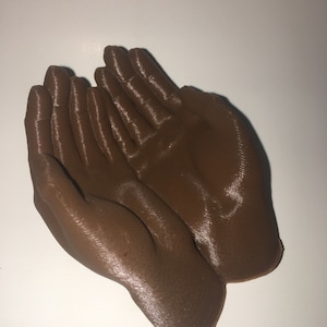 May include: A brown 3D printed sculpture of two hands cupped together.