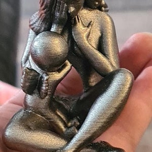 K&ouml;nnte beinhalten: Eine silberfarbene Metallsculptur einer Mutter und eines Kindes. Die Mutter h&auml;lt das Kind fest an sich, und beide Figuren haben einen ruhigen Ausdruck.