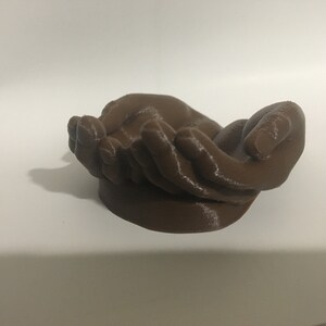 K&ouml;nnte beinhalten: Eine 3D-gedruckte Skulptur aus zwei ineinander gelegten H&auml;nden, aus braunem Kunststoff.