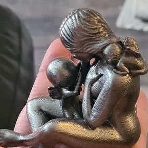 K&ouml;nnte beinhalten: Eine silberfarbene 3D-gedruckte Skulptur einer Mutter und eines Kindes. Die Mutter h&auml;lt das Kind fest an ihrer Brust, und das Kind hat seine Arme um den Hals der Mutter gelegt.