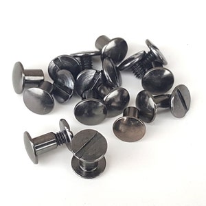 May include: A group of black metal screw-on studs with a flat head and a slotted screw. The studs are scattered on a white surface.