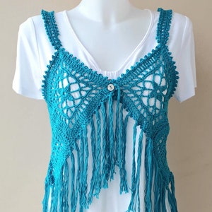 May include: A turquoise crochet vest with fringe detailing. The vest has a button closure at the centre front.