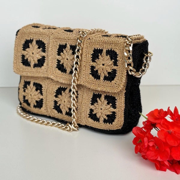 Borsa in crochet quadrata rigida con cordino colore oro e nero. Chiusura con calamita. Tracolla con catena