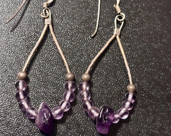 Pendientes de aro alargados en forma de lágrima, elaborados artesanalmente en plata de ley con cuentas de amatista.