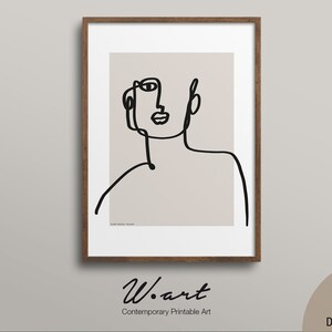 Può includere: Stampa artistica incorniciata con un disegno a tratto minimalista nero di un volto su sfondo beige. L'opera d'arte è in una cornice di legno marrone. La parte inferiore della cornice presenta il testo "W. art Contemporary Printable Art" e un'icona di download digitale.