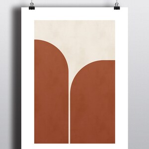 May include: Abstract art print with a geometric design featuring two rounded shapes in burnt orange and a smaller white shape in the center.