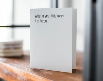 May include: A white card with the text "What a year this week has been." printed in black.