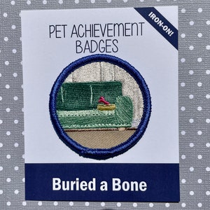 Puede incluir: Parche de planchado con un sofá verde y un hueso rojo enterrado en él. El parche es azul y blanco y dice "Pet Achievement Badges" y "Buried a Bone".