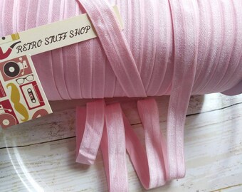 Puede incluir: Un rollo de elástico rosa doblado, también conocido como FOE, con una etiqueta que dice "Retro Stuff Shop".