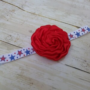 May include: Red satin flower headband with a white and blue star patterned elastic band.