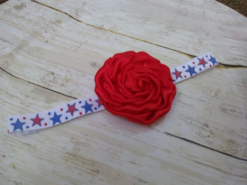 May include: Red satin flower headband with a white and blue star patterned elastic band.