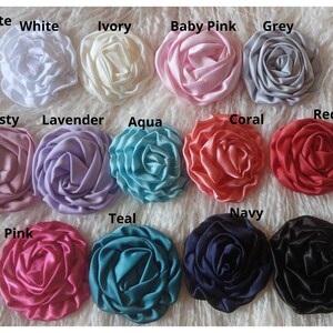 May include: A collection of 12 3-inch satin rosettes in various colors, including white, ivory, baby pink, grey, dusty rose, lavender, aqua, coral, red, hot pink, teal, navy, and black.