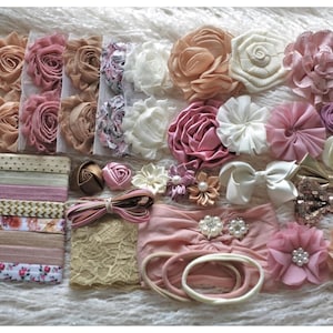 May include: A collection of hair accessories including fabric flower clips, elastic headbands with various patterns, lace bands, sequined bows, and satin bows. The items feature shades of pink, cream, gold, and brown with pearl accents.