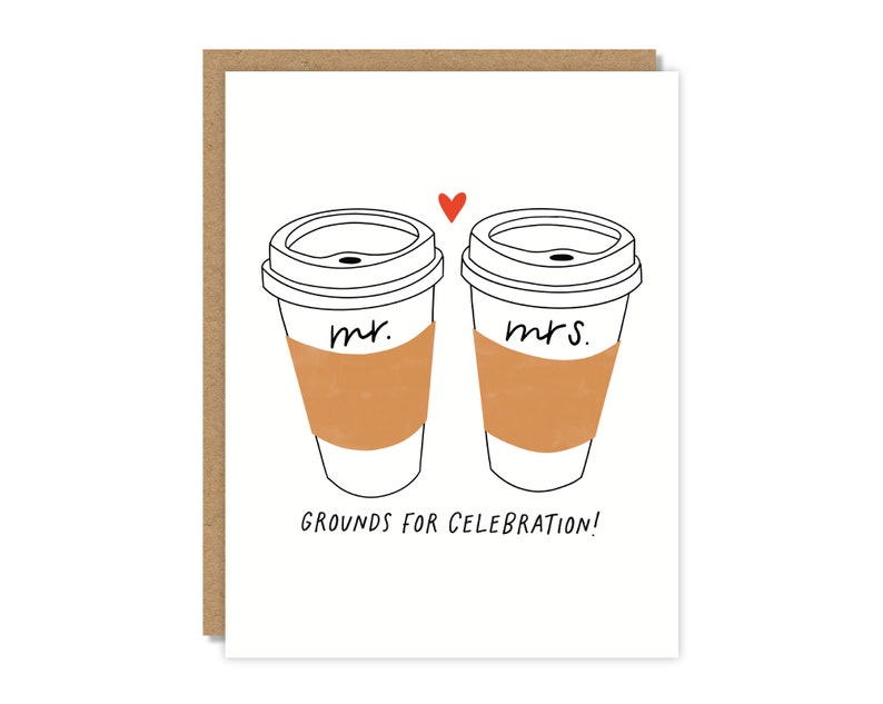 May include: A white card with a black line drawing of two coffee cups. The cups have the words "Mr." and "Mrs." written on them. A red heart is drawn above the cups. The text "GROUNDS FOR CELEBRATION!" is written below the cups.